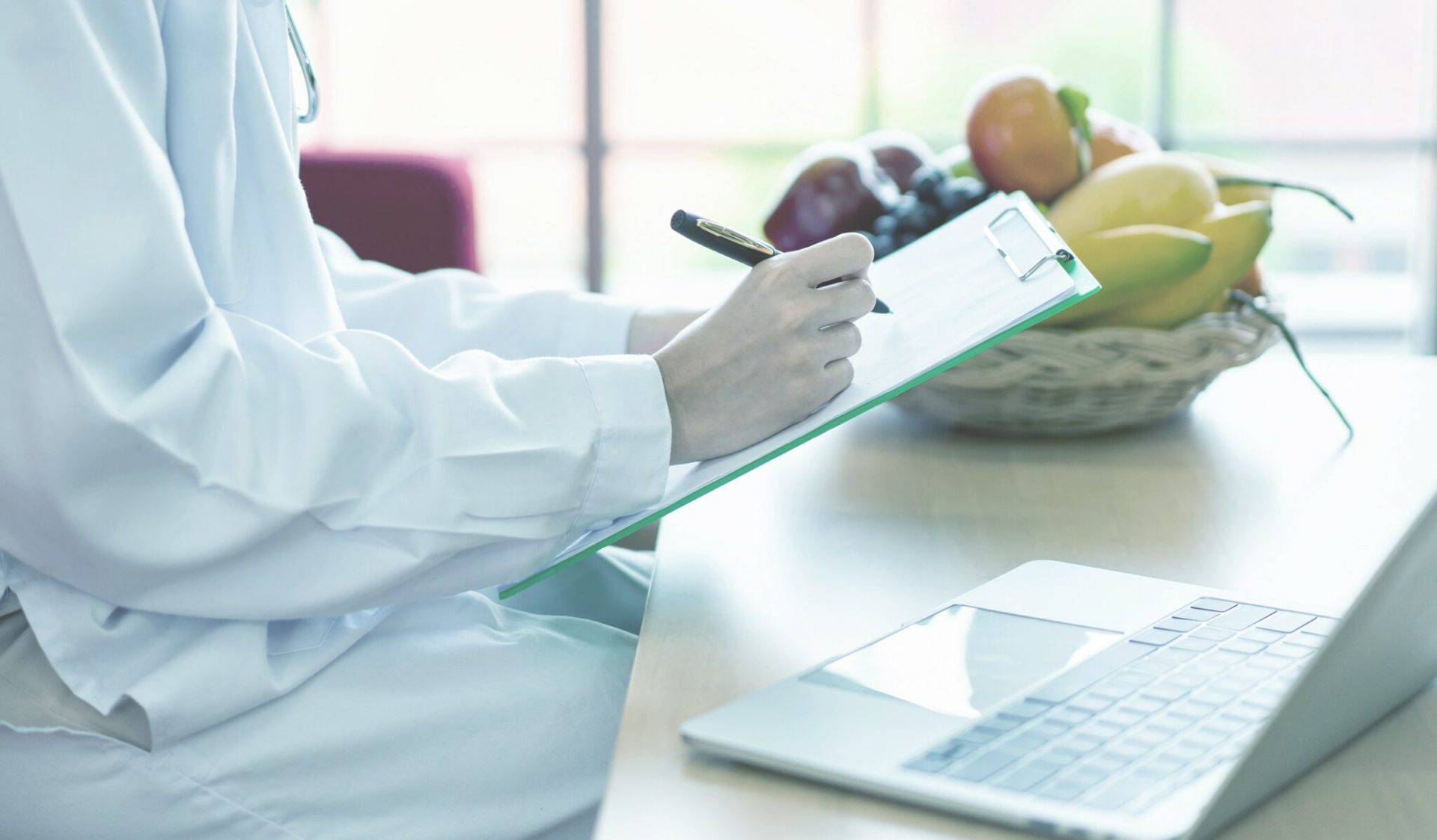 Dietista tomando notas en consulta de nutrición con alimentos saludables