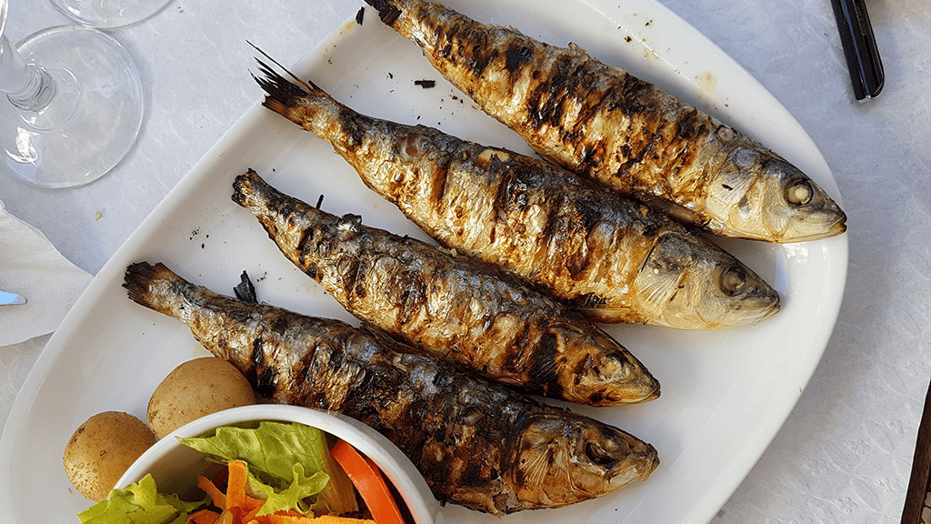 Los 10 alimentos con más creatina (y por qué no bastan para rendir) 21 Sardinas a la plancha servidas en un plato con patata y ensalada