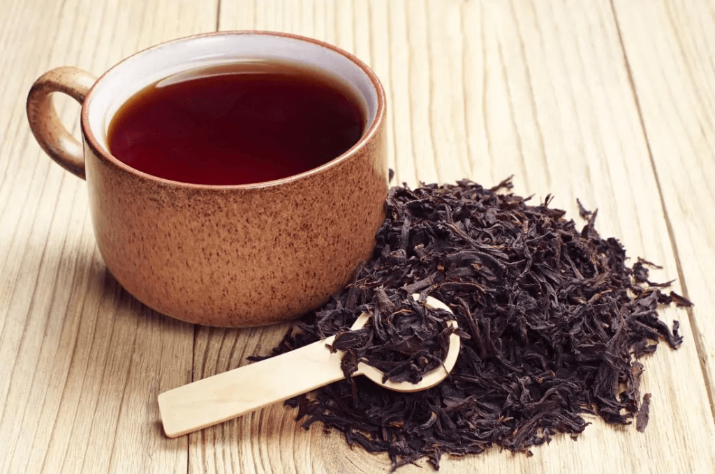 El mejor té para perder grasa: qué dice la evidencia (sin humo) 5 Taza de té negro junto a un montoncito de hojas secas sobre una mesa de madera